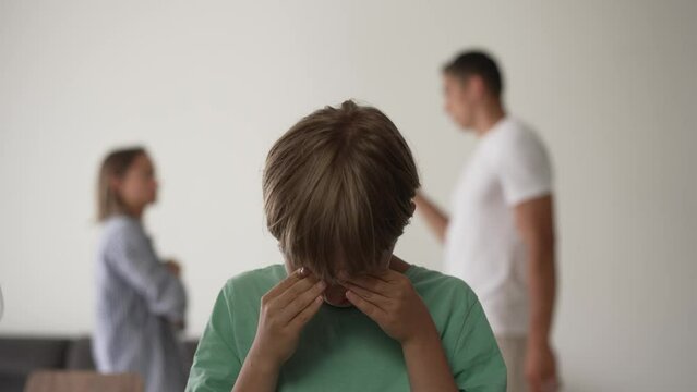 Kid son feels upset while parents fighting at background, sad little girl frustrated with psychological problem caused by mom and dad arguing, family conflicts or divorce impact on child concept
