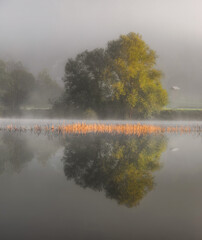 Autumn mist by the lake with beautiful calm reflections.