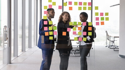 Confident attractive woman leader of project explain information on sticky notes to African and...