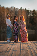 Naklejka premium Three young beautiful girls are resting on the lake.