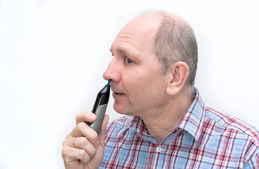 Caucasian man 50 years old, man shaving his nose hair using a nose trimmer.