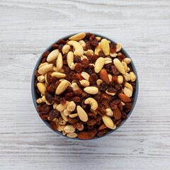 Raw Trail Mix with Nuts and Fruits in a Bowl on a white wooden background, top view. Flat lay, overhead, from above.