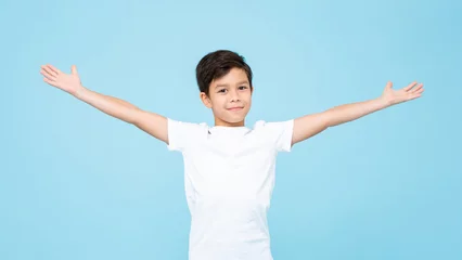 Foto op Canvas Cute smiling handsome mixed race boy with open arms in isolated light blue color studio background © Atstock Productions
