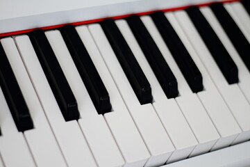 Closeup of piano keyboard with glossy black and white keys as a music background, selected focus,...