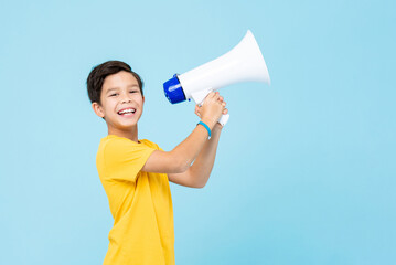 Cute little boy holding megaphone in studio isolated light blue color background
