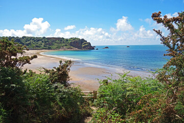 A beautiful panoramic view of Ouaisne Bay with verdant scenery and cliffs with blue sea and blue  sky and fluffy white clouds sky in Jersey in the beautiful Channel Islands U.K.