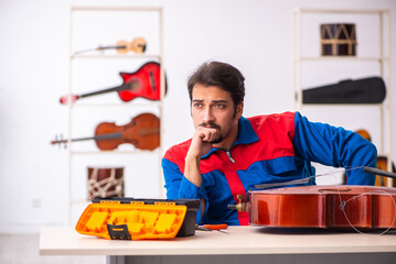 Young male repairman repairing musical instruments at workplace