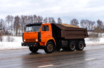 Fototapeta na wymiar The orange truck is transporting rubble. Dump truck close-up. Truck in motion.
