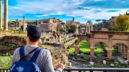 Tourist man with panoramic view on ancient ruins of Roman Forum. Skyline from Palatine Hill in city...