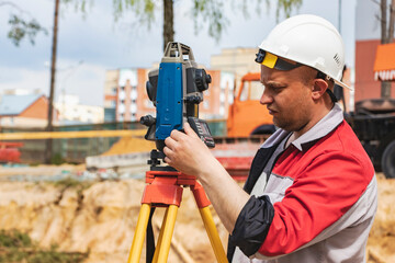 Construction of a residential area. Geodetic stakeout. Surveyor at a large construction site. A man...