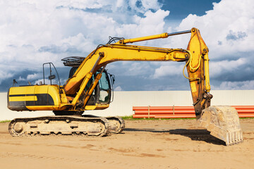 Powerful excavator at a construction site against a blue cloudy sky. Earthmoving construction equipment. Modern building machines.