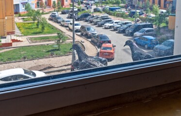 Two pigeons are sitting behind the glass on the window ledge