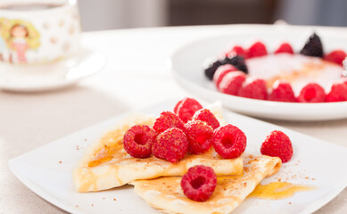 breakfast of pancakes with fresh raspberries on table