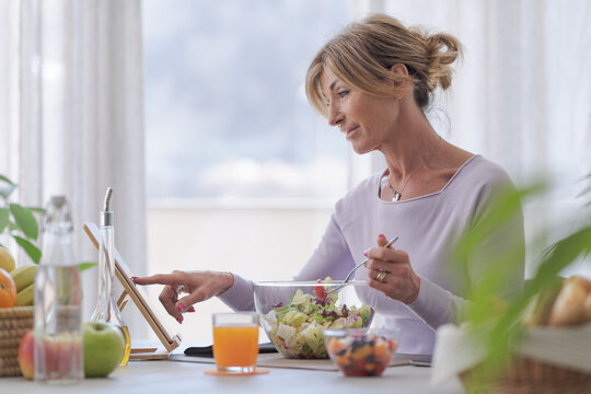 Woman having lunch and connecting with her tablet