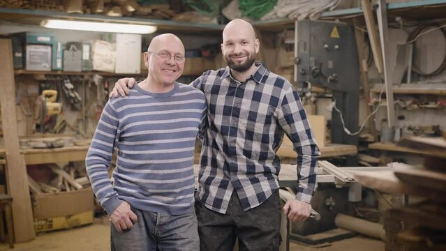 Father and son in their family carpentry workshop. The father passes on his experience and business to his son.