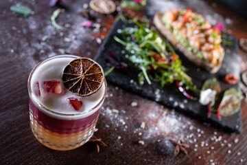 fresh stylish layered pink sour grapefruit cocktail with foam and sandwich