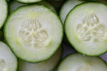 Sliced slices of green cucumber macro photo as background