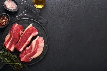 Steak beef. Raw steak New York with rosemary and spices on old iron plate on old dark stone background. Top view. Mock up.