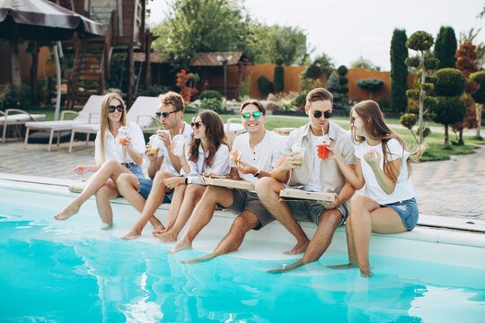 Group of young people having fun at backyard poolside party, enjoying sunny summer days outdoor, drinking cocktails and eating pizza and sushi..