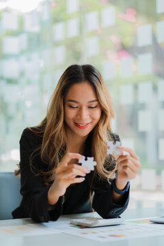 Asian businesswoman playing puzzle symbolic problem solving and working financial accounting work concept.