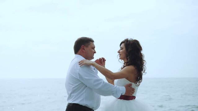 The newlyweds dance on the sea beach, the bride and groom on the sea