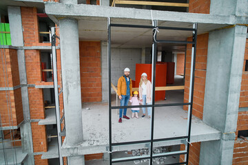 Fototapeta na wymiar Man with wife and child standing inside residential building under construction. Urban district with newly constructed apartment building and family new residents real estate buyers. Drone view