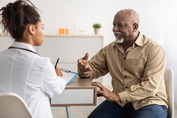 Black patient talking to doctor during appointment - obrazy, fototapety, plakaty