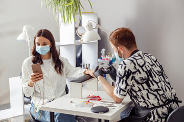 Naklejka premium Female client getting treatment manicure procedure in salon