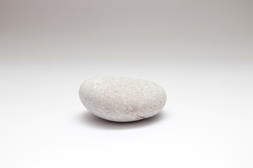 Fototapeta na wymiar One grey pebble on white background