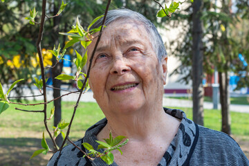 Happy Senior woman with gray hair in blooming park spring.