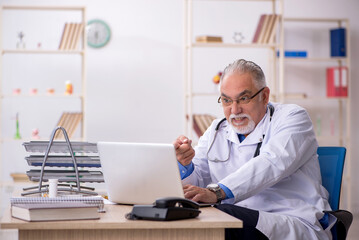 Obraz premium Old male doctor working in the clinic