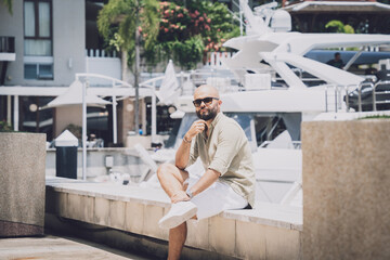 Fototapeta na wymiar Portrait of a fashion young man posing at marina and yahts background