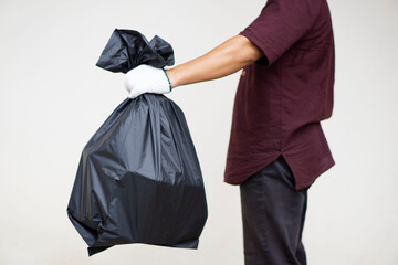 Man holds black plastic bag that contains garbage inside. Concept : Waste management. Environment problems. Daily chores. Throw away rubbish.