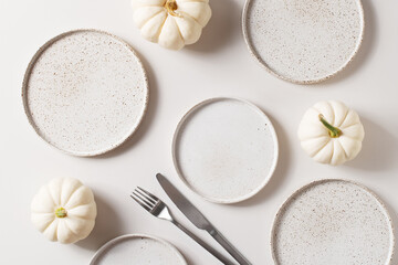 Some white ceramic plates with tableware and pumpkins serving background - obrazy, fototapety, plakaty