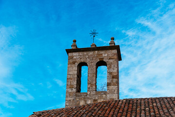 Bell tower of a medieval stone church in the historic town of Atienza in Guadalajara, Spain. Low angle view against blue sky