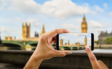 tourist holds up camera mobile at big ben in london england