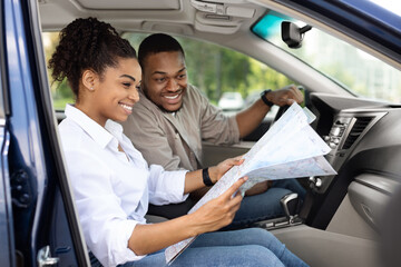 Black Couple Sitting In Car Holding Map Choosing Travel Destination