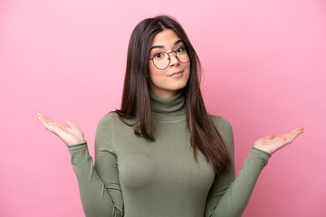 Young Brazilian woman isolated on pink background With glasses and having doubts