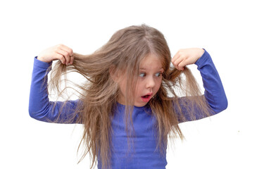 Isolated caucasian little girl of 5 6 years holding hair being in shock about hair losing or having...