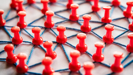 Netzwerk mit vielen Verbindungen mit roten Stecknadeln und Faden
