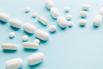White pills on a pastel background. Capsules and round pills close-up. Healthcare and medicine.