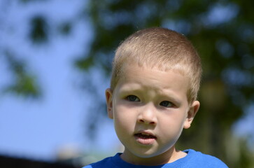 Portrait of a blond boy 5 years old. Face close-up, blue eyes, serious expression.