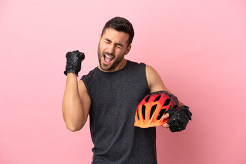 Young cyclist man isolated on pink background celebrating a victory - obrazy, fototapety, plakaty