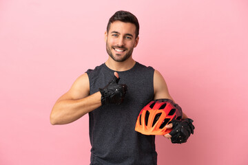 Young cyclist man isolated on pink background giving a thumbs up gesture - obrazy, fototapety, plakaty