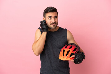 Young cyclist man isolated on pink background frustrated and covering ears - obrazy, fototapety, plakaty