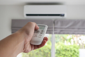 Hand with remote control directed on air conditioner