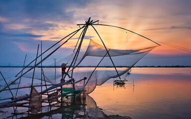 A woman is fishing in a flooded field during sunset in Chau Doc district, An Giang province, Vietnam.