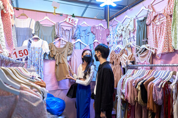 Shop full of clothes in a fair with a lesbian couple shopping inside