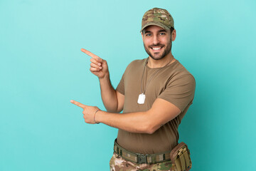 Military with dog tag over isolated on blue background pointing finger to the side and presenting a...