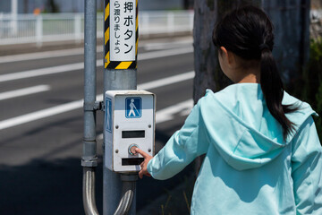 交差点の障害者用ボタンを押す子供の姿 - obrazy, fototapety, plakaty